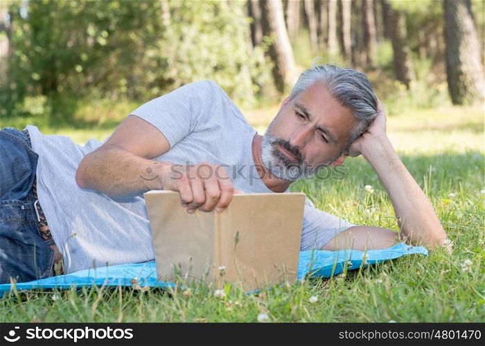 man lyingsitting in the grass reading a book