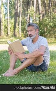 man lyingsitting in the grass reading a book
