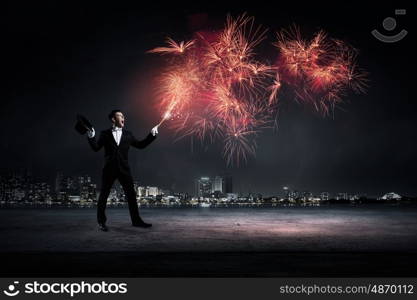 Man magician with cylinder hat. Young cheerful businessman making tricks with magic hat