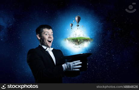 Man magician with cylinder hat. Young cheerful businessman making tricks with magic hat