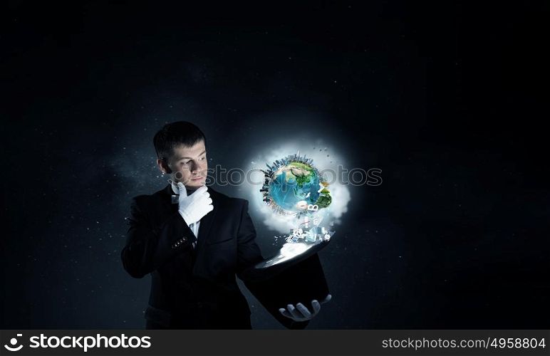 Man magician with cylinder hat. Young cheerful businessman making tricks with magic hat. Elements of this image are furnished by NASA