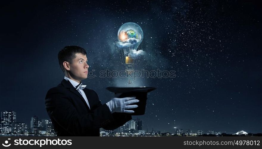 Man magician with cylinder hat. Young cheerful businessman making tricks with magic hat. Elements of this image are furnished by NASA