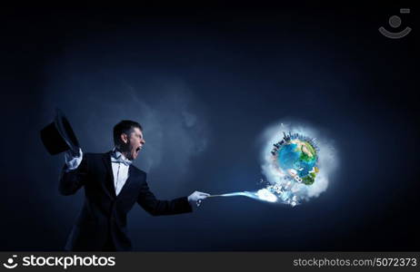 Man magician with cylinder hat. Young cheerful businessman making tricks with magic hat. Elements of this image are furnished by NASA