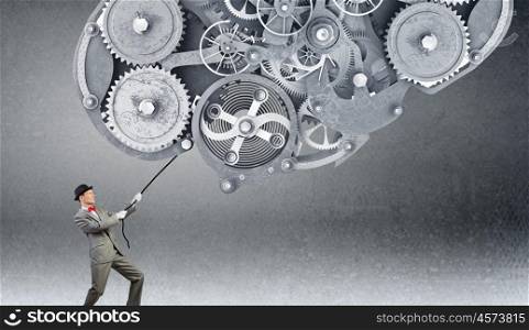 Man make gears mechanism work. Young businessman pulling gears mechanism with rope