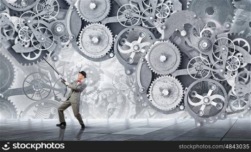 Man make gears mechanism work. Young businessman pulling gears mechanism with rope