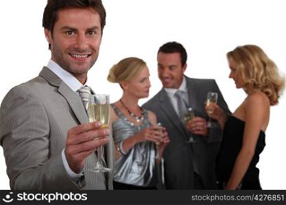 Man making a toast with champagne as his friends chat in the background