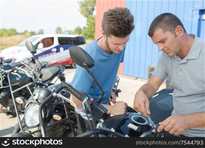 Man making adjustment to motorcycle with spanner