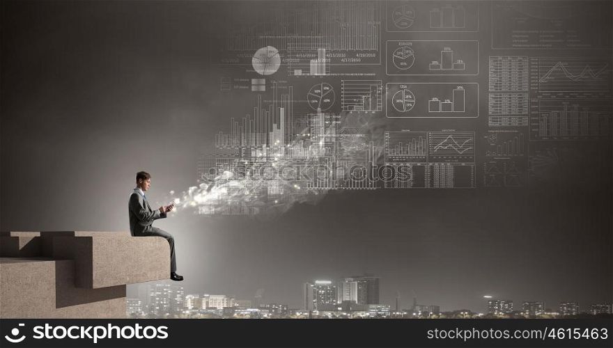 Man making calls with his mobile. Young businessman sitting on building top and using mobile phone