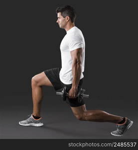 Man making exercise, lifting weight on a grey background