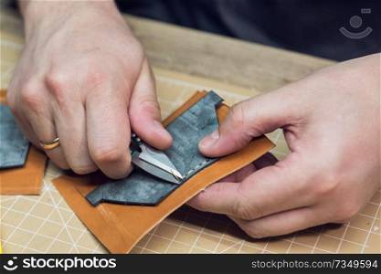 Man making leather wallet at a workshop. Concept of handmade craft production of leather goods.. Concept of handmade craft production of leather goods.