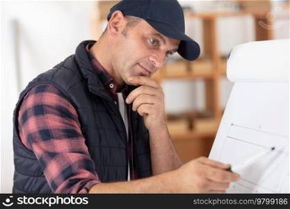 man making notes standing at table in modern workshop