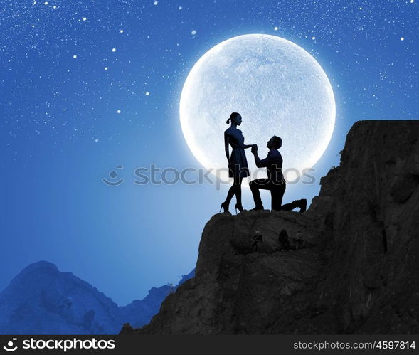 Man making proposal. Silhouettes of romantic couple under the moon light