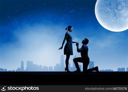 Man making proposal. Silhouettes of romantic couple under the moon light