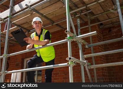 Man, male builder, foreman, construction worker, surveyor, engineer or architect on site holding a clipboard and drinking a mug of coffee or tea