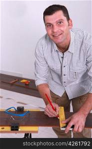 Man marking a floorboard with a pencil