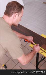 Man marking off laminate flooring with pencil
