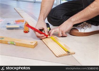Man marking on plywood with measuring and pencil