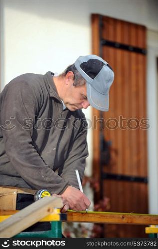 Man marking plank before cutting it