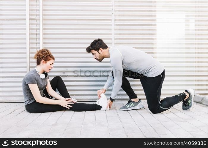 man massaging stretched leg woman