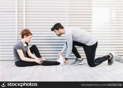 man massaging stretched leg woman