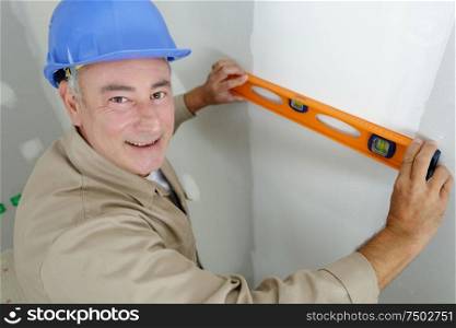man measures the wall with a level