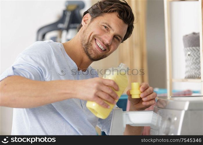 man measuring fabric conditioner by washing machine