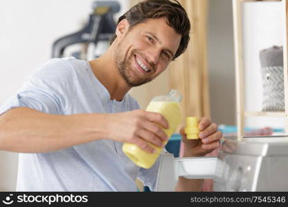 man measuring fabric conditioner by washing machine