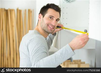 man measuring home furniture with measure tape