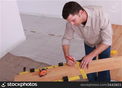 Man measuring plank of laminate flooring