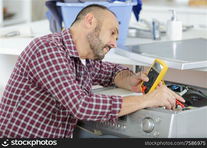man measuring the voltage of a washing machine