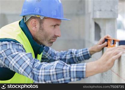 man measuring wall with construction level