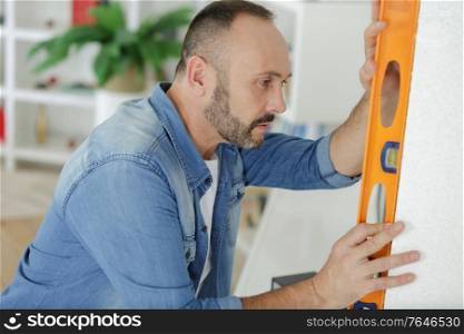man measuring wall with level
