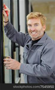 man measuring window prior to installation