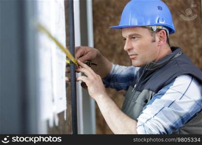 man measuring window prior to installation of roller shutter