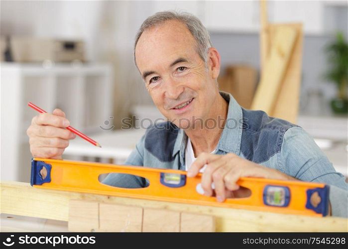 man measuring wood piece for furniture assembling