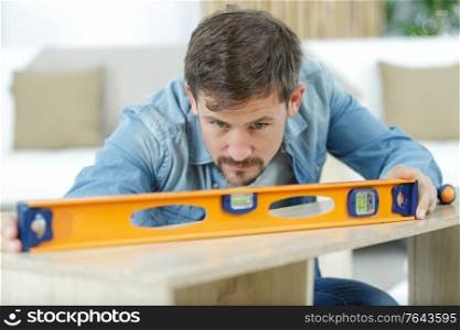 man measuring wood piece for furniture assembling