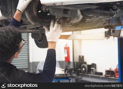 Man mechanic inspection service maintenance car suspension change wheels.He note or writing for checking and hand pointing. checking engine in garage showroom dealership
