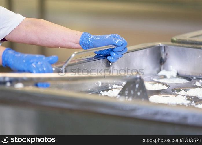 Man mixing raw cheese in the stainless tank during the fermentation process at the cheese manufacturing plant .. Man mixing raw cheese in the stainless tank during the fermentation process at the cheese manufacturing plant.