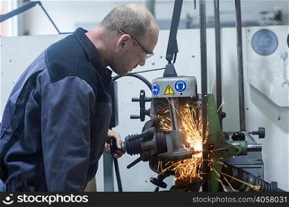 Man monitoring grinding machine in workshop