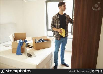 Man Moving Into New Home And Unpacking Boxes In Bedroom