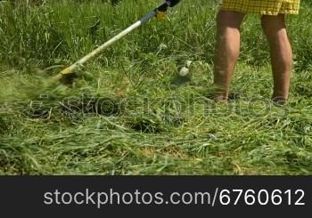 Man mowing the grass in the backyard with grass cutter
