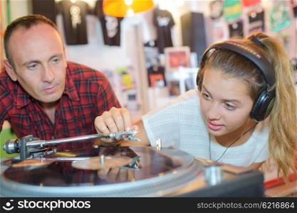 Man nervously watching young lady playing a vinyl record