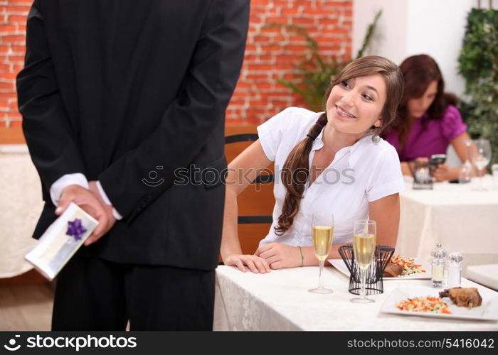 Man offering gift to woman in restaurant