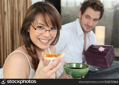 Man offering girlfriend present at breakfast