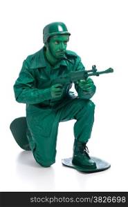 Man on a green toy soldier costume standing on one knee with riffle isolated on white background.