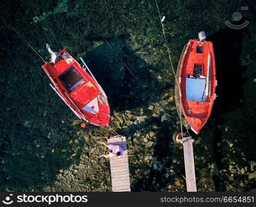 Man on a wooden pier with fishing boats top aerial view drone shot, Sithonia, Greece