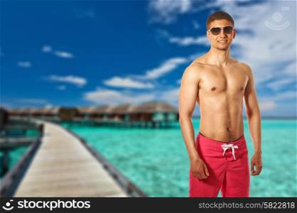 Man on beach with water bungalows at Maldives. Collage.