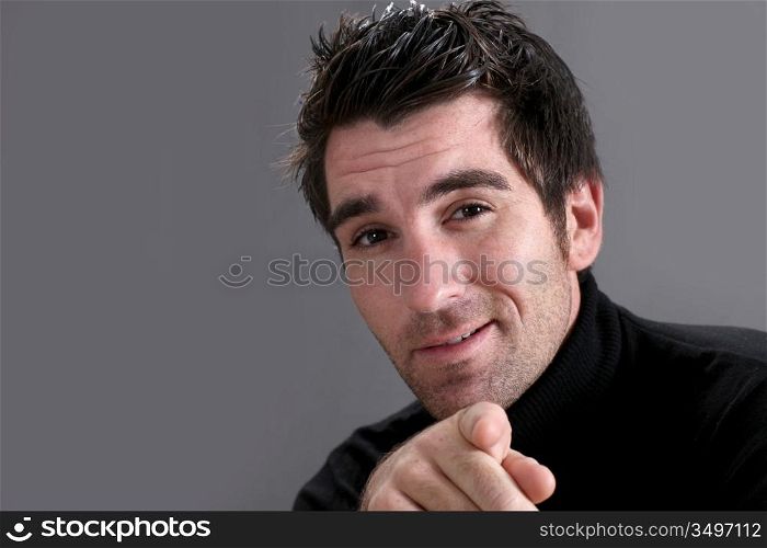 Man on black background pointing at camera