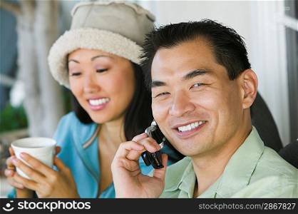 Man on Cell Phone with Woman Drinking Coffee