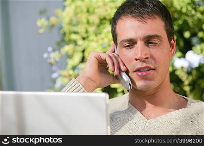 Man on cellphone with laptop